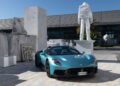 A turquoise Maserati, a symbol of Italian luxury, is parked in front of a marble astronaut statue and stone slabs outside a modern building—a scene fit for the ultimate MCPURA Driving Experience.