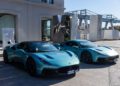 Two turquoise Maserati sports cars are parked side by side in an industrial outdoor setting with large marble slabs and metal structures, embodying the spirit of Italy and the thrill of the MCPURA Driving Experience.