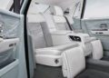 Luxury car interior with white and light blue leather seats, intricate door panel designs, and bespoke rear center console and footrests, inspired by the elegance of Rolls-Royce Phantoms.