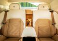 The back seat of a bespoke Rolls-Royce with beige leather upholstery; Bailey, a small dog, is visible between the seats, looking forward.