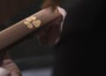 A person holds a bespoke Rolls-Royce wooden object, dedicated to a dog, featuring an engraved paw print design on its surface.