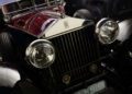 Close-up view of the front grille and headlights of a classic maroon Rolls-Royce car, showcasing the bespoke details and the iconic Rolls-Royce emblem on the radiator.