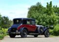 Vintage black and burgundy Rolls-Royce parked on a paved driveway, surrounded by trees and greenery, highlights the bespoke elegance of classic Phantoms.