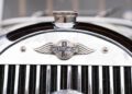 Close-up of a vintage Morgan Plus Four grille featuring the iconic Morgan emblem with wings and a chrome finish, celebrating the brand's timeless style ahead of its 75th Anniversary.