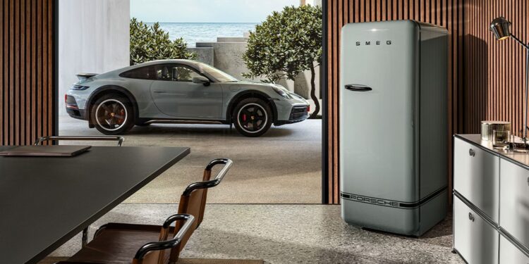 A modern kitchen with a retro-style SMEG refrigerator showcases a perfect collaboration of classic design, while a sleek Porsche sports car is parked outside near the ocean.