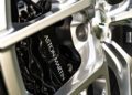 Close-up of an Aston Martin wheel showcasing the silver alloy rim and black brake caliper with the “Aston Martin” logo.