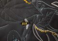 Close-up of black leather with embroidered patterns of leaves and a bee in yellow, white, and grey threads, inspired by the Rolls-Royce Honors 100 Years Of Phantom With Groundbreaking Private Collection.