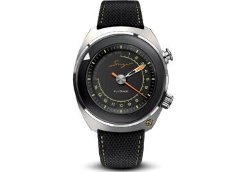 A round black and silver wristwatch with a black textured strap, yellow and orange accents, and two side buttons. The dial reads “Singer” and “Flytrack”—a striking addition to any collection of best luxury watches.