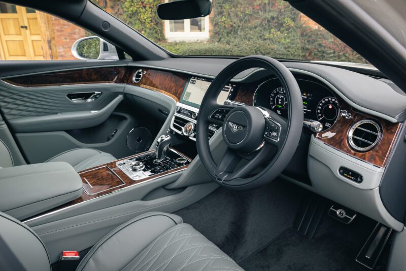 Luxury car interior inspired by Bentley, featuring quilted leather seats, wood trim, and a modern dashboard with digital displays—a tribute to legendary sedans and exclusive Mulliner touches.