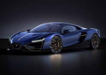 A sleek blue sports car with gold accents, low profile, aerodynamic curves, and large alloy wheels, inspired by Vittori’s new hybrid hypercar with Pininfarina design, is shown in a dimly lit studio setting.