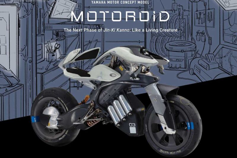 Futuristic Yamaha MOTOROiD motorcycle prototype displayed in front of a technical blueprint background. The design emphasizes advanced technology and innovative engineering.