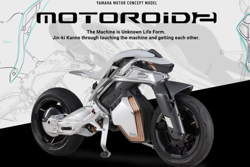 Futuristinis Yamaha MOTOROiDΛ motociklo prototipas rodomas techninio projekto fone su aprašomu tekstu virš ir po dviračiu.