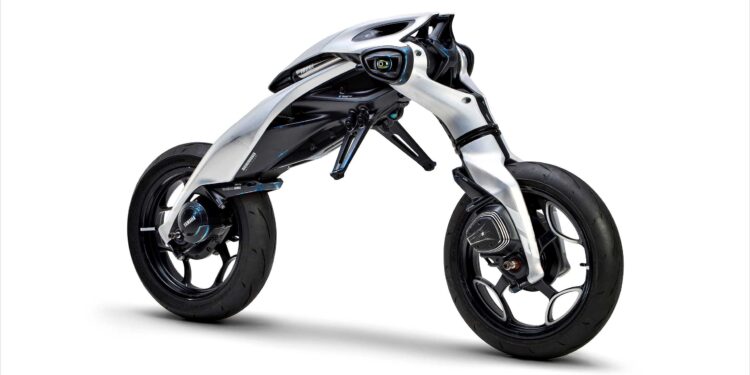 Futuristic, minimalist Yamaha MOTOROiDΛ electric motorcycle with exposed frame, two large wheels, and a sleek, aerodynamic white and black body design against a white background.
