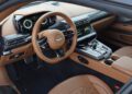 Review: 2025 Aston Martin Vanquish Coupe features a luxury car interior with tan leather seats, digital dashboard, multi-function steering wheel, and central touchscreen display with modern controls and buttons.