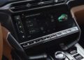 Review: 2025 Aston Martin Vanquish Coupe – Close-up of the car's infotainment screen displaying drive mode options, surrounded by control buttons and elegant brown interior accents.