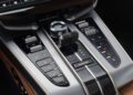 Close-up of the 2025 Aston Martin Vanquish Coupe center console, showcasing the gear selector, electronic parking brake, climate control buttons, and drive mode switch.