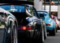 Several classic sports cars, including a black and a blue Porsche 993, are parked in a row on a street in Durham, NC, viewed from the rear during Luftgekühlt 11.