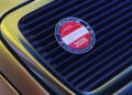 Close-up of a Porsche Classic Restoration Challenge 2025 badge displayed on the vented rear engine cover of a gold Porsche Classic vehicle.