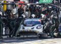 A 2025 Porsche race car with a shark mouth design receives a pit stop service from a team of mechanics during an IMSA WeatherTech SportsCar event.