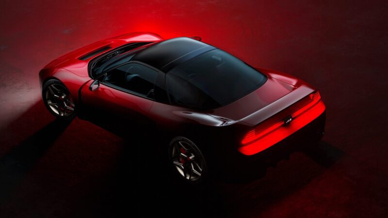 A red Honda NSX restomod with a black roof is shown from above and behind, illuminated by red tail lights on a dark red surface.