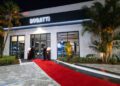 The entrance of Bugatti Broward at night features a red carpet, flanked by two people in suits, with illuminated palm trees on both sides—perfectly setting the stage for a hypercar experience.