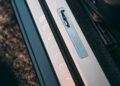 Close-up of a car door sill with "BENTLEY" illuminated and a plaque engraved: "Handcrafted in England. We are proud to build," part of the Bentley Honors Wartime Heroes with the Czech Squadron Collection.