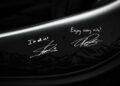 Close-up of a black carbon fiber surface on the Project Viva Revealed: One-of-One McLaren 750S Spider, featuring white handwritten signatures and messages like "I'm all in!" and "Enjoy every mile!" that bring Las Vegas to life.