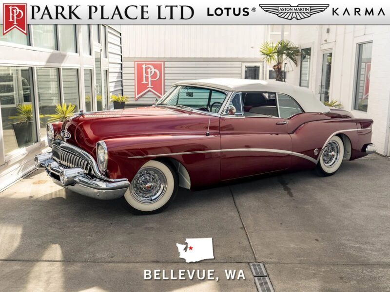 A classic maroon Buick convertible with a white soft top is parked in a dealership showroom in Bellevue, WA, showcasing the elegance of Classic Muscle Cars.