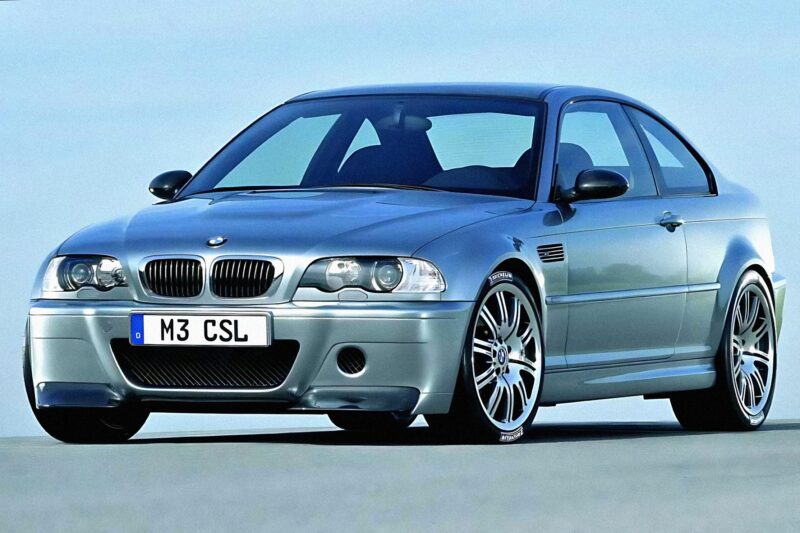 A silver two-door BMW coupe with "M3 CSL" on the license plate, parked on a flat surface against a clear blue sky, this modern-day E46 M3 sports a timeless design that could barely disguise its racing pedigree.