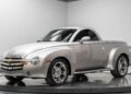 A silver Chevrolet SSR convertible pickup truck, one of the best 2000s cars, is displayed indoors on a turntable, featuring chrome wheels and a retro-styled body.