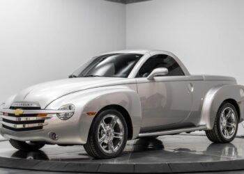A silver Chevrolet SSR convertible pickup truck, one of the best 2000s cars, is displayed indoors on a turntable, featuring chrome wheels and a retro-styled body.