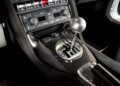 Close-up view of a car's carbon fiber center console featuring a gated manual gear shifter and various control knobs, showcasing the iconic style of The Last Lamborghini With Rear Wheel Drive and a Manual Transmission.