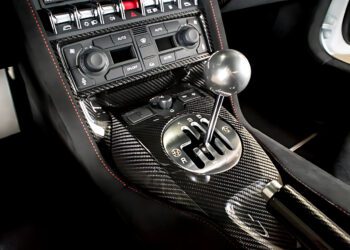 Close-up view of a car's carbon fiber center console featuring a gated manual gear shifter and various control knobs, showcasing the iconic style of The Last Lamborghini With Rear Wheel Drive and a Manual Transmission.