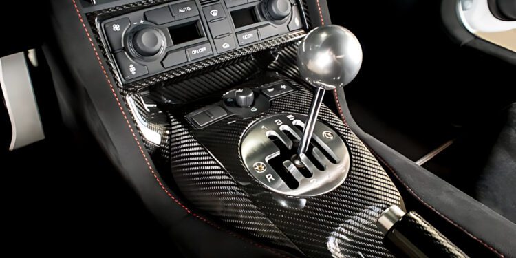 Close-up view of a car's carbon fiber center console featuring a gated manual gear shifter and various control knobs, showcasing the iconic style of The Last Lamborghini With Rear Wheel Drive and a Manual Transmission.