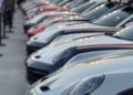 A row of luxury sports cars parked outdoors at an event, with people standing in the background. Feature Exclusive: 2025 Icons of Porsche Dubai showcases the latest models in a stunning automotive display.