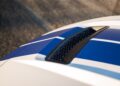 Close-up of the 2025 Shelby GT350 hood with blue and white racing stripes and a black hexagonal-patterned air vent.