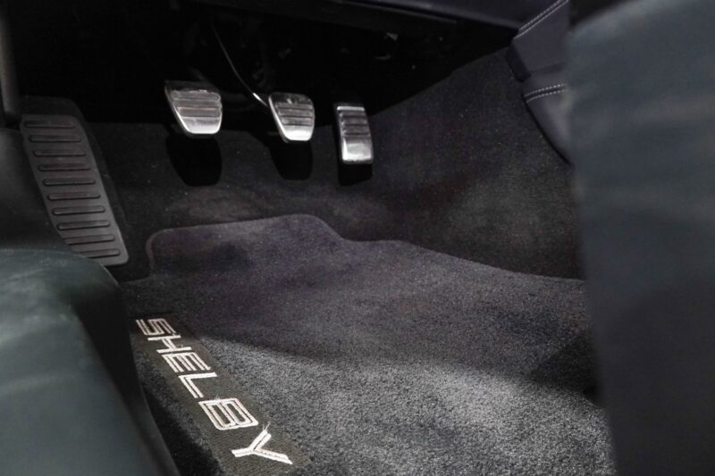 View of a car’s footwell with three metal pedals and a carpeted floor mat labeled “SHELBY”—a detail highlighted in the Review: 2025 Shelby GT350.