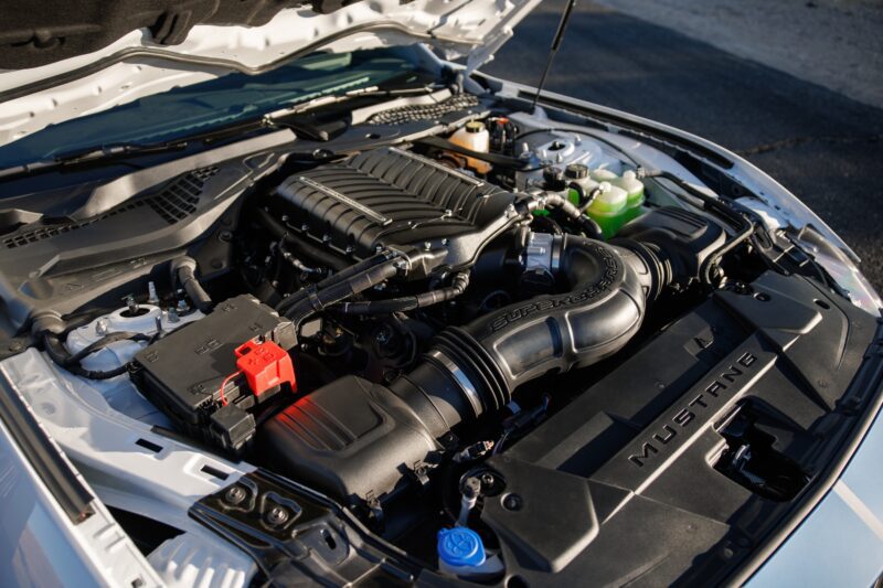 Close-up view of a Ford Mustang engine bay with the hood open, showcasing a supercharger and various components—perfect for a Review: 2025 Shelby GT350.