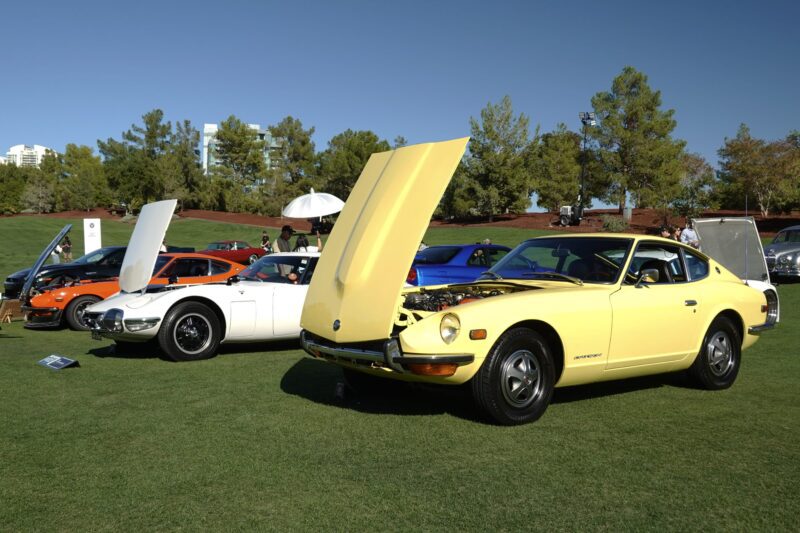 Several classic sports cars, including a yellow Datsun 240Z with its hood open, are displayed on a grassy lawn at an outdoor car show reminiscent of Wynn Concours 2025: Hypercars World Debuts and Elevated Hospitality in Las Vegas.