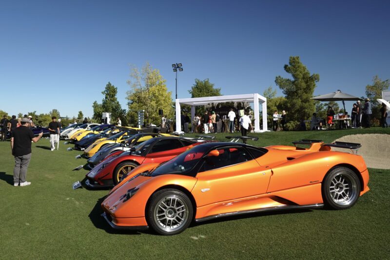A row of colorful sports cars is parked on a grassy area at the Wynn Concours 2025, where hypercars make world debuts and guests enjoy elevated hospitality at Las Vegas’ premier automotive event under white tents.
