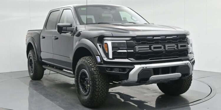 A black Ford F-150 Raptor pickup truck, known for its style and comfort among luxury trucks, is parked in a white, well-lit studio with a circular rotating platform.