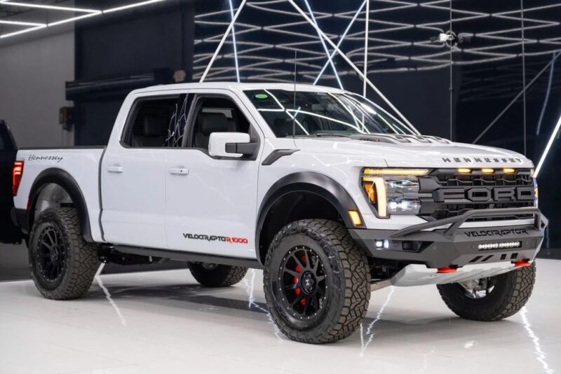 A white Hennessey VelociRaptor 1000 luxury truck is parked indoors under bright, geometric ceiling lights, showcasing its blend of capability and sophisticated design.