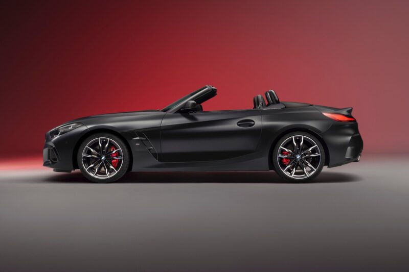A matte black End of the Road: 2026 BMW Z4 Final Edition convertible sports car with the top down, shown in profile view against a gradient red background.