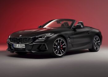 A matte black BMW Z4 convertible sports car is shown in a studio with a red gradient background, highlighting the End of the Road: 2026 BMW Z4 Final Edition Breaks Cover in bold, striking style.