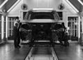 Two workers inspect and assemble an unfinished car on a production line inside a well-lit automotive factory, where Range Rover expands its 2026 Sport lineup with SV Black and SV Bespoke Editions.