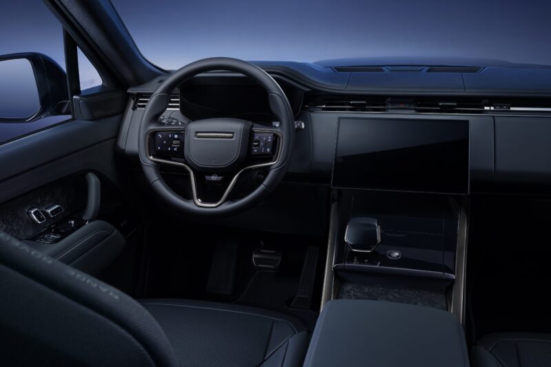 A modern car interior inspired by Range Rover Expands 2026 Sport Lineup with SV Black, featuring a black steering wheel, digital dashboard, large touchscreen display, and minimalist design with dark upholstery.