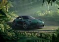 A stunning green Porsche Sonderwunsch 911 GT3 is parked on a dirt road, surrounded by dense, lush jungle vegetation with sunlight filtering through the trees.