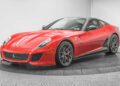 A red Ferrari 599 GTO with black alloy wheels is on display in a well-lit showroom with a gray background—a must-have addition for any supercar collection.