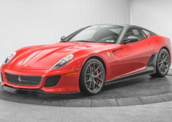 A red Ferrari 599 GTO with black alloy wheels is on display in a well-lit showroom with a gray background—a must-have addition for any supercar collection.