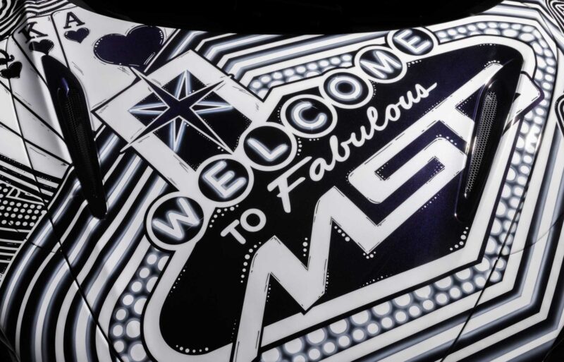 Close-up of a car hood featuring a black and white "Welcome to Fabulous MST" graphic with playing card designs and stylized lights, inspired by Project Viva Revealed: One-of-One McLaren 750S Spider Brings Las Vegas to Life.